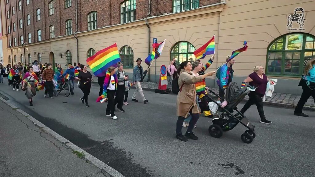 Deltagare med regnbågsflaggor och barnvagn i pridetåget i Kalmar 2026